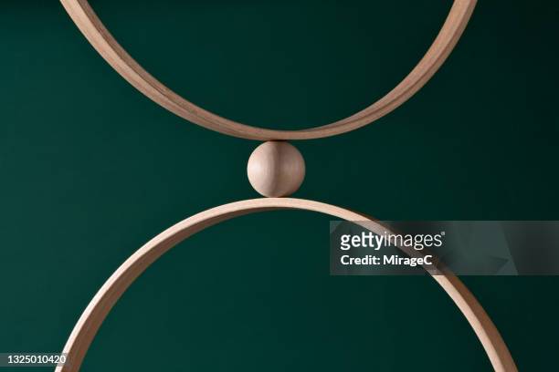 wooden sphere squeezed between two rings - exclusion concept stock pictures, royalty-free photos & images