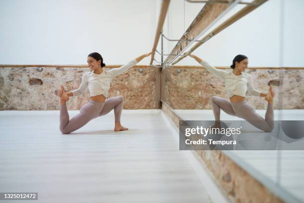 a young woman doing barre exercises in front of the mirror. - bars stockfoto's en -beelden