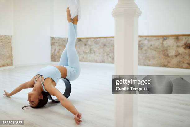 a young woman doing aero yoga exercises with a wheel. - acroyoga stock pictures, royalty-free photos & images