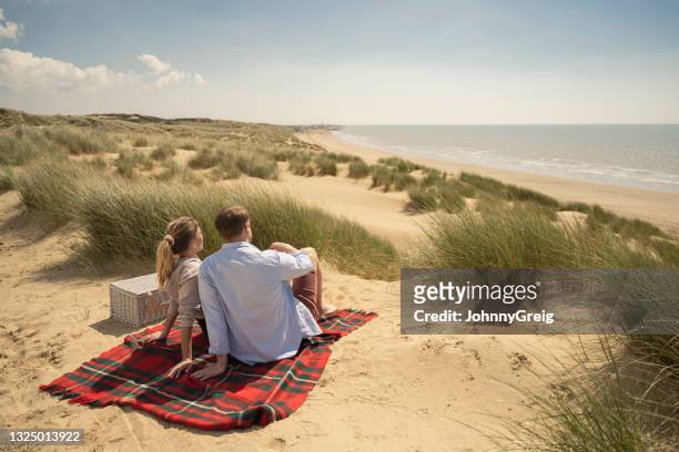 砂丘からの眺めを見てカジュアルな服装のカップル - camber sands ストックフォトと画像