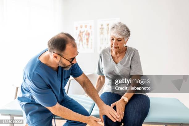 mujer mayor que tiene su rodilla examinada por un médico. - articulaciones fotografías e imágenes de stock