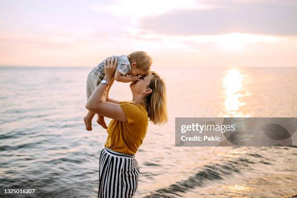 joven madre unida en la playa del mar - mom holding baby fotografías e imágenes de stock