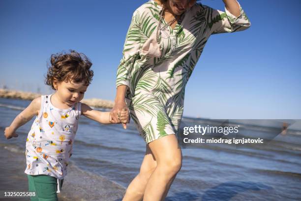 little boy and mother having fun on seashore during sunny day - larnaca stock pictures, royalty-free photos & images