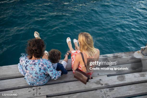 little boy enjoying summer day on wooden dock with his mother and aunt - limassol stock pictures, royalty-free photos & images