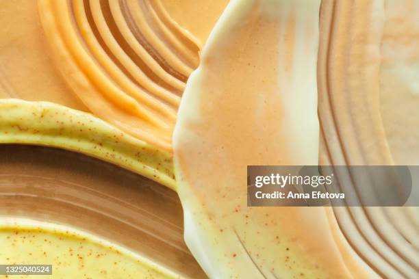 textured smears of yellow yogurt, orange ice cream and lemon sorbet on brown background. flat lay style and close-up - savoury food stock pictures, royalty-free photos & images