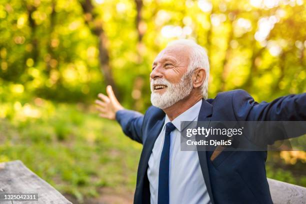 felice uomo d'affari senior godendosi il suo tempo nella natura. - arms outstretched foto e immagini stock