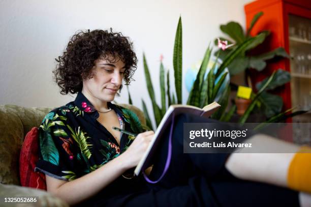 non-binary person writing a diary - schreiben stock-fotos und bilder