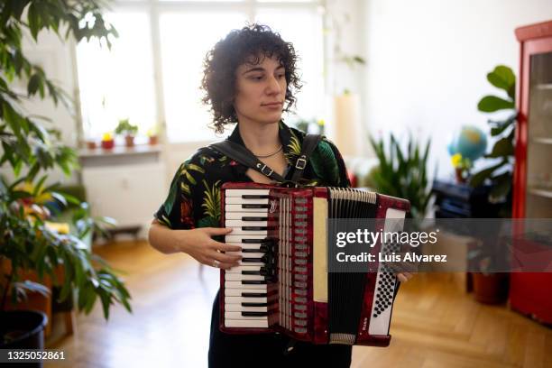 non-binary person playing vintage accordion at home - accordionist - fotografias e filmes do acervo