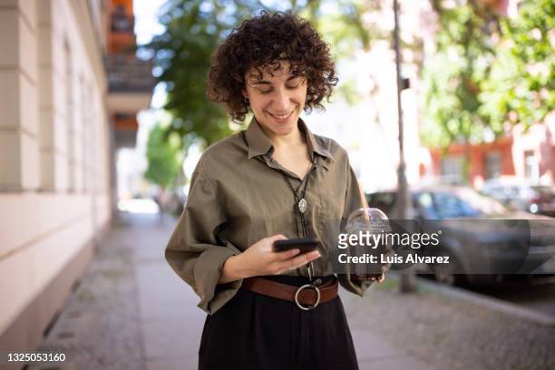 non-binary person texting on phone outside - coffee car design stock pictures, royalty-free photos & images