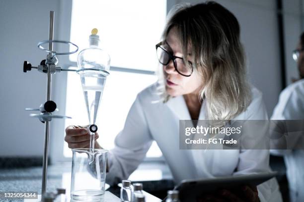 woman working in a laboratory, using digital tablet - separating funnel stock pictures, royalty-free photos & images