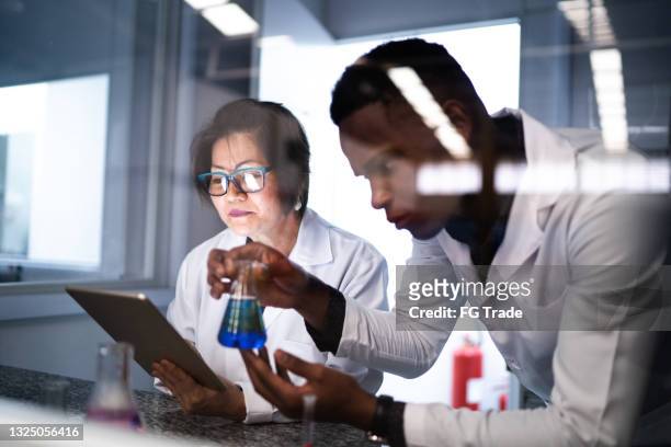 colleagues working and using digital tablet in laboratory - young man scientist stock pictures, royalty-free photos & images