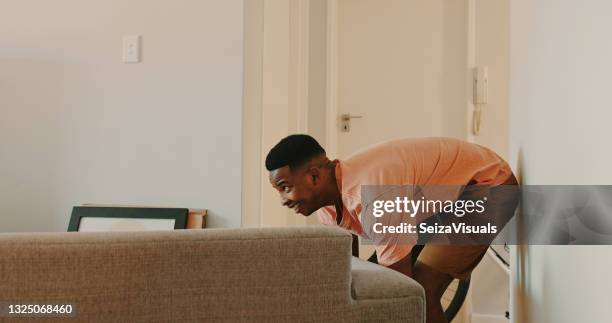 shot of a young man moving a couch at home - pushing stock pictures, royalty-free photos & images