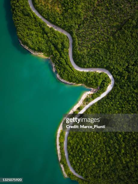 vista aérea de la pintoresca carretera de montaña y el lago - campo verde fotografías e imágenes de stock