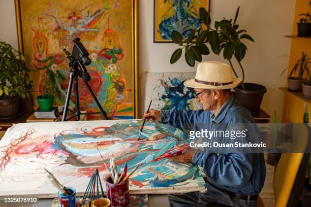 moderner senior-künstler, der den online-kunstkurs mit der kamera filmt, während er seinen schüler über action-malerei unterrichtet - artist painter stock-fotos und bilder