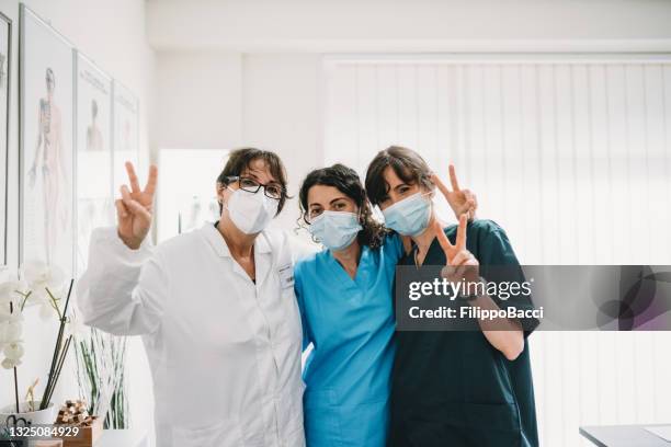 teamwork of three healthcare workers celebrating together, looking at camera - protective face mask happy stock pictures, royalty-free photos & images