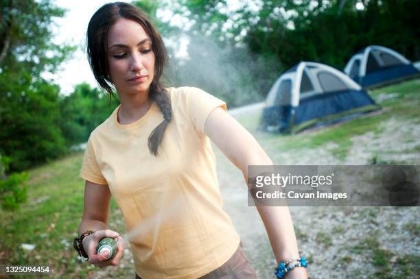 a woman uses insect repellent while camping in everglades national park, florida. - fly spray stock pictures, royalty-free photos & images