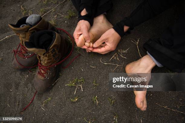 a man inspects his toes while hiking on the loast coast, california. - blister stockfoto's en -beelden