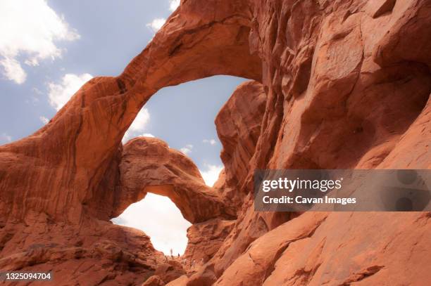 people exploring two arches.  arches national park, moab, utah. - double arch foto e immagini stock