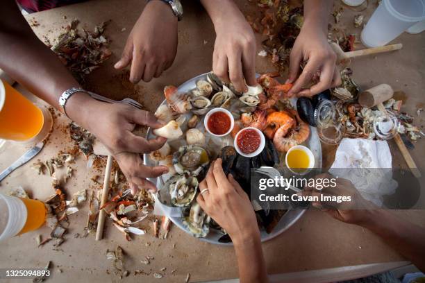 tourists dig into a seafood feast. - eating seafood stock pictures, royalty-free photos & images