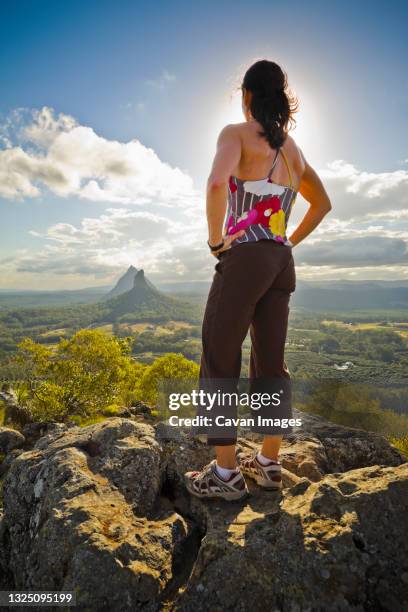 a woman stands on the summit of mount ngun ngun in the glasshouse mountains, queensland, australia - glass house mountains - fotografias e filmes do acervo