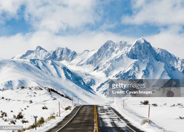 road leading toward snow covered mountains - mammoth stock-fotos und bilder