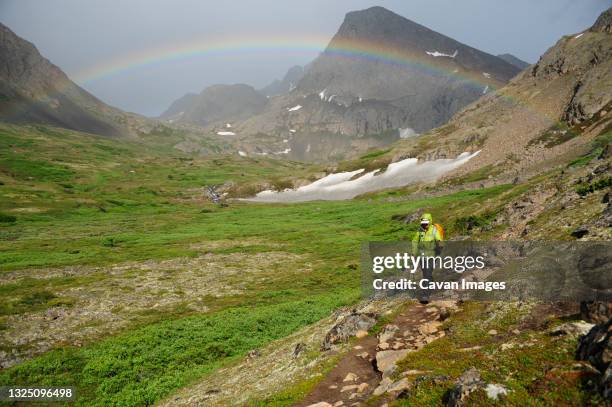 backpacker hiking under a rainbow in chugach state park near anchorage, alaska. - chugach state park stock-fotos und bilder