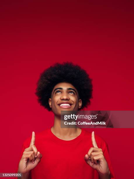 african american man with african hairstyle standing over isolated red background - black guy with red hair stockfoto's en -beelden