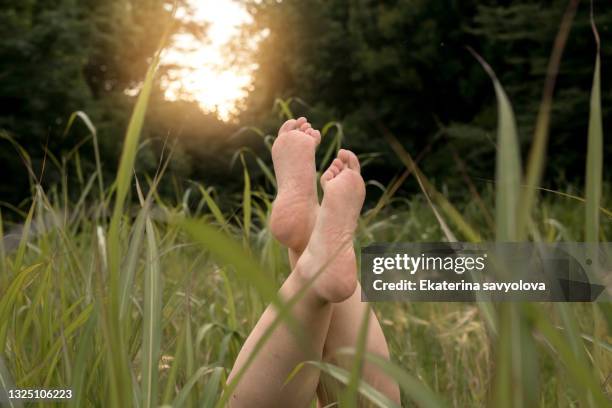 bare feet lie on the green grass. close-up. - womans bare feet fotografías e imágenes de stock