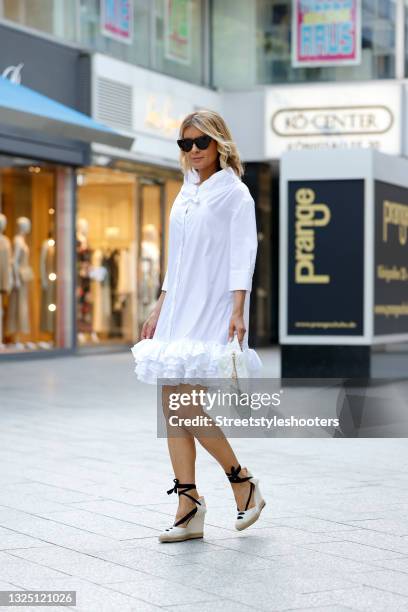 Influencer Gitta Banko wearing a white mini dress with ruffles by Armargentum, beige and black Espadrilles by Schutz, a white hip bag by Chanel and...