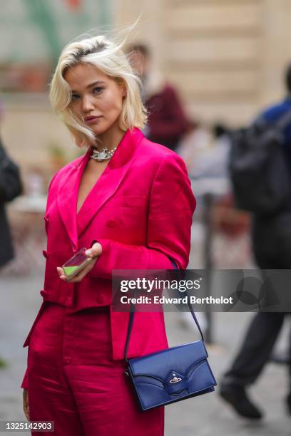 Guest wears a beaded pearl bejeweled necklace, black bras a neon pink / fuchsia lustrous silky / shiny blazer jacket, matching flared slit pants, a...