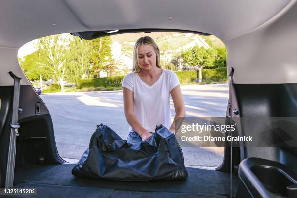 young woman at car trunk with bag - duffle bag stock pictures, royalty-free photos & images