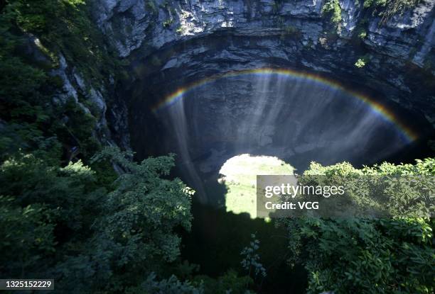 Rainbow is seen at a 290-meter deep karst sinkhole, located near the village of Luoquanyan, on June 23, 2021 in Xuan en County, Enshi Tujia and Miao...