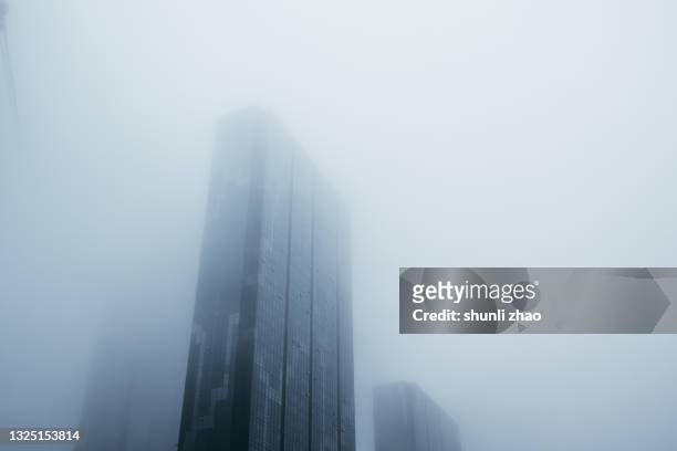 skyscrapers shrouded in heavy fog - many cities in china shrouded in fog photos et images de collection