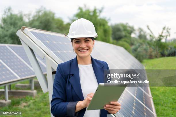 una donna manager ingegnere i̇n controllo casco di sicurezza con tablet un funzionamento del sistema di pannelli solari presso la stazione solare - engineering foto e immagini stock