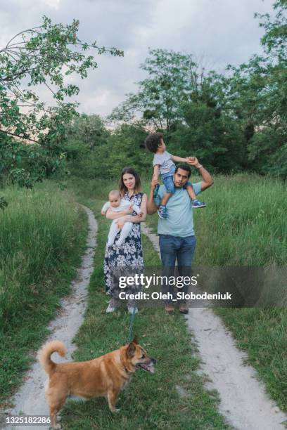 mixed race family with two children and dog walking outside in summer - real family stock pictures, royalty-free photos & images