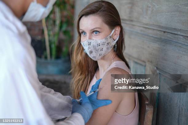 female tourist receiving vaccination from healthcare worker in bali - receiving treatment concerned stock pictures, royalty-free photos & images