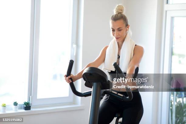 mujer joven en bicicleta estática - exercise bike fotografías e imágenes de stock