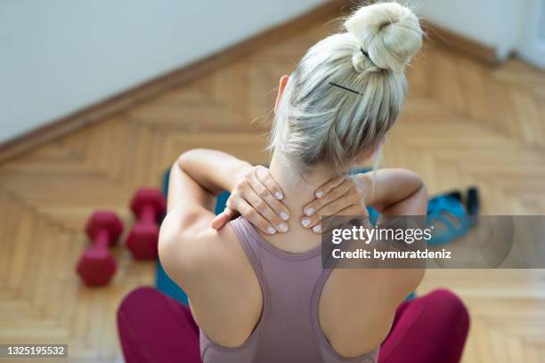 woman rubbing her neck - women sport injury imagens e fotografias de stock