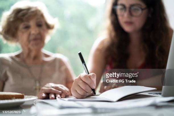 granddaughter helping granddaughter with doing home finances - financial advisor with family stock pictures, royalty-free photos & images
