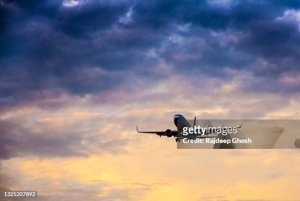 aeroplane flying around colorful clouds - plane wing stock pictures, royalty-free photos & images