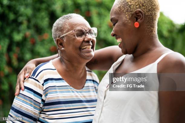 mother and daughter embracing at home - mature woman daughter stockfoto's en -beelden