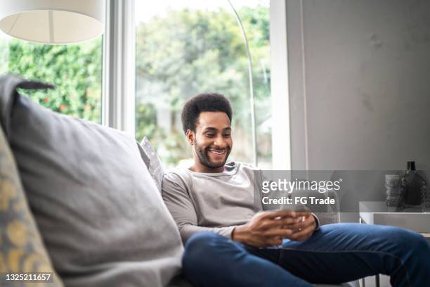 man using smartphone at home - good news 個照片及圖片檔