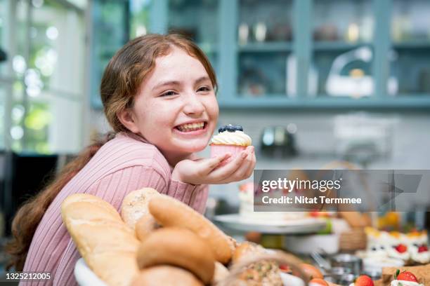 ready-to-eat cupcakes. teenage girls having fun making dessert class. she is showing cupcakes after making the finish. - children cooking school stock-fotos und bilder