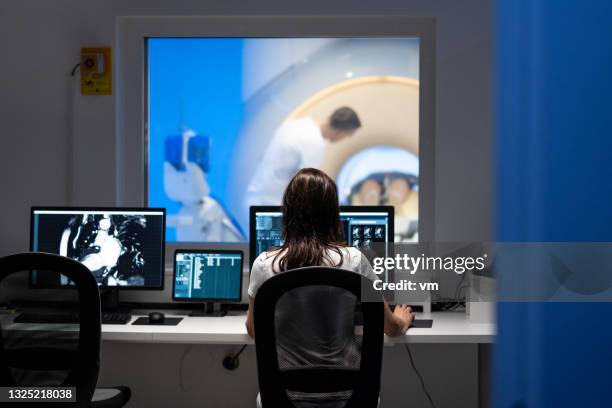 doctor analyzing mri results in office next to scanner - mri scan stock pictures, royalty-free photos & images