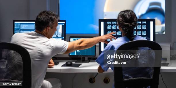 !!back view of two doctors analyzing mri scan results. man pointing at images on monitor screen. - radiologist 個照片及圖片檔