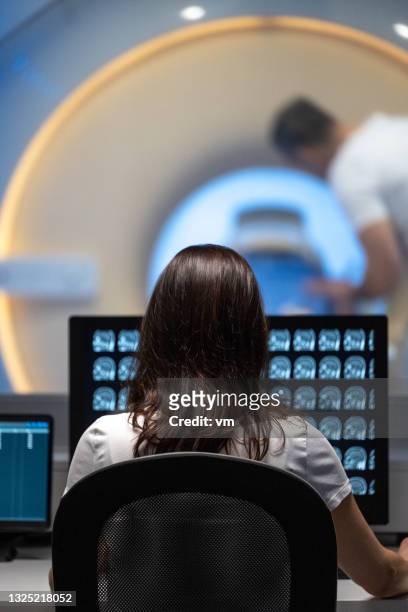 doctor analyzing mri results in office next to scanner - mri scanner stock pictures, royalty-free photos & images
