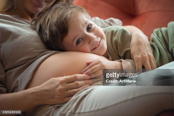 niño pequeño escuchando el vientre de su madre embarazada - baby touching belly fotografías e imágenes de stock