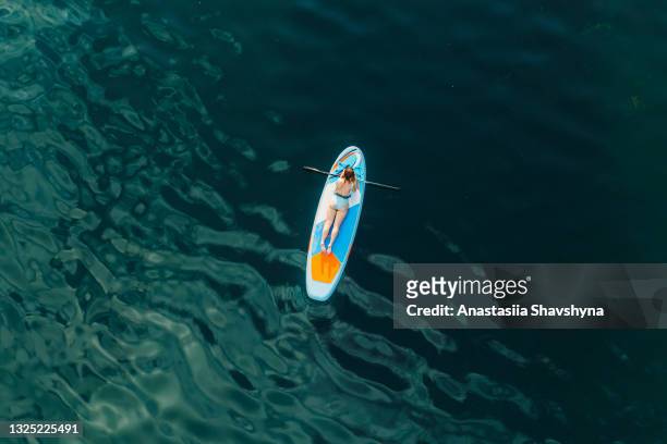 scenic aerial view of a young woman paddleboarding at the beautiful lake during summer sunset - pension ukraine stock pictures, royalty-free photos & images