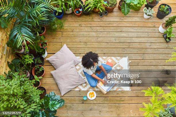 portrait of woman sitting in her garden using a laptop - tuinterras stockfoto's en -beelden