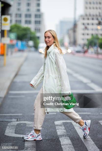 Sonia Lyson is seen wearing sneaker New Balance, Louis Vuitton rain coat, green Bottega Veneta bag, beige jogger pants Pangaia on June 24, 2021 in...